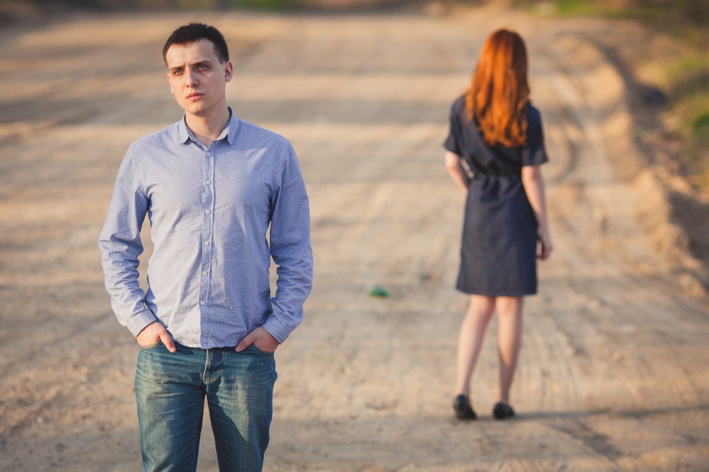 sad man and red woman stand on the dirt road