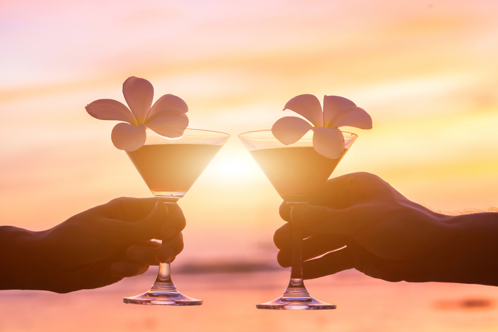 tropical cocktails on the beach, couple of hands with glasses